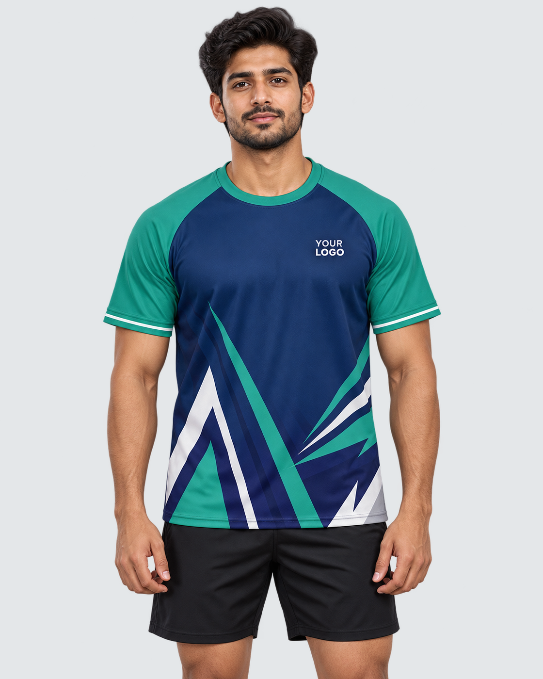 Front model photo of a navy and teal angular geometric sports jersey with YOUR LOGO placeholder, worn with plain black sports shorts