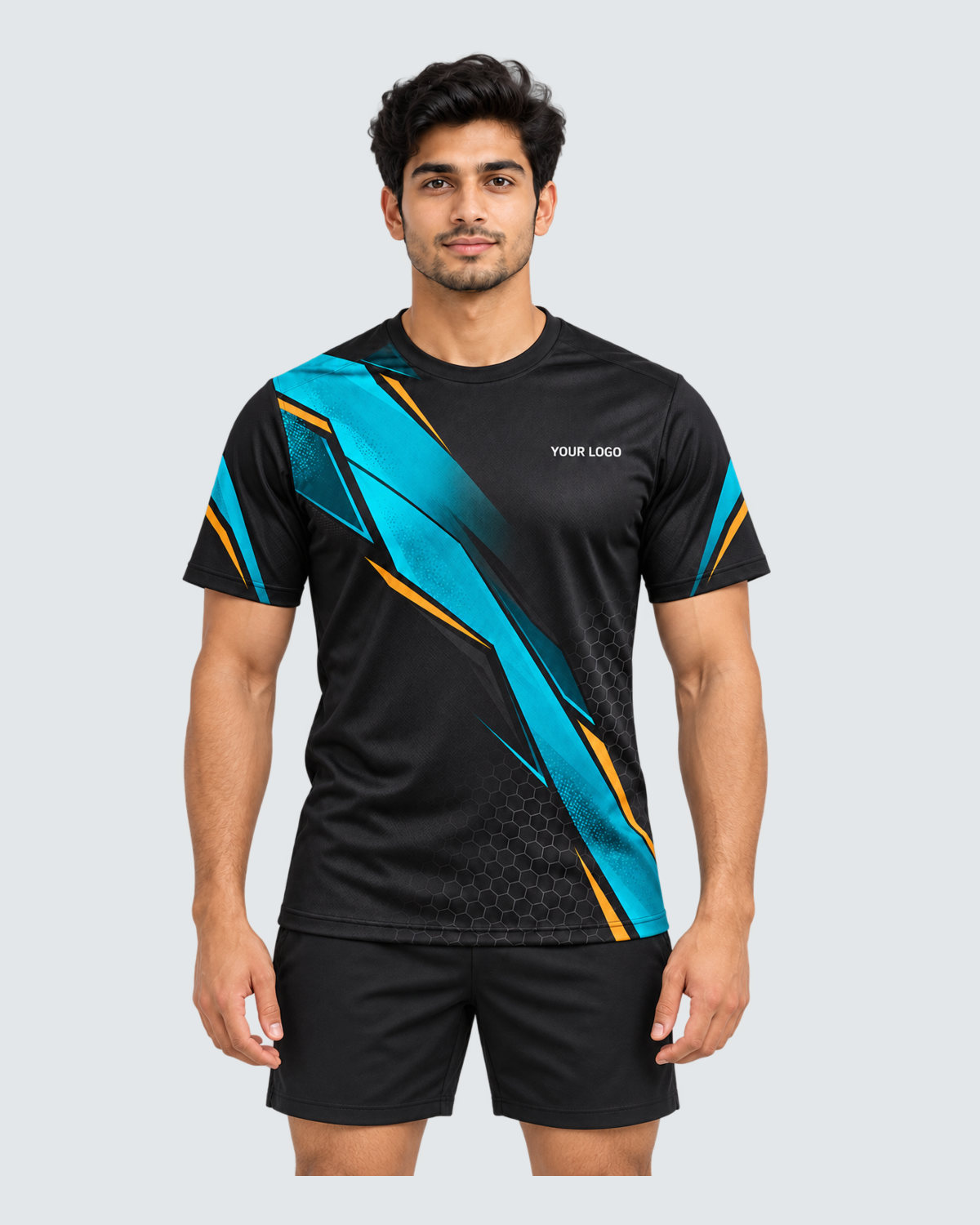 Carbon Tide, Front view with YOUR LOGO chest placement; Indian male model, black sports shorts, solid #E4E7E9 background, portrait 4:5