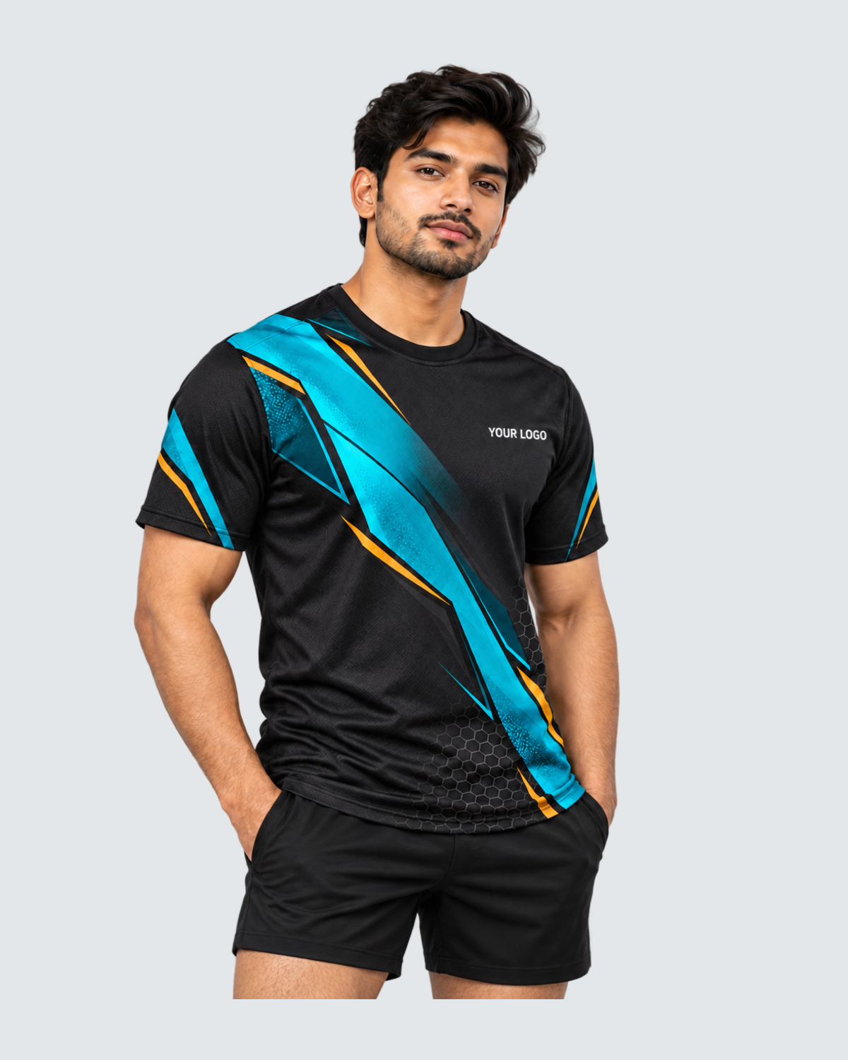 Carbon Tide, Three-quarter front view; Indian male model, black sports shorts, solid #E4E7E9 background, portrait 4:5