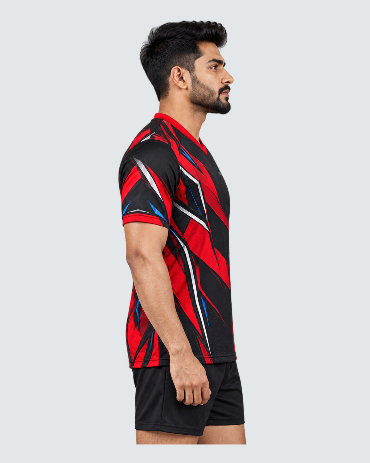 Crimson Flux, Left profile; Indian male model, black sports shorts, solid #E4E7E9 background, portrait 4:5